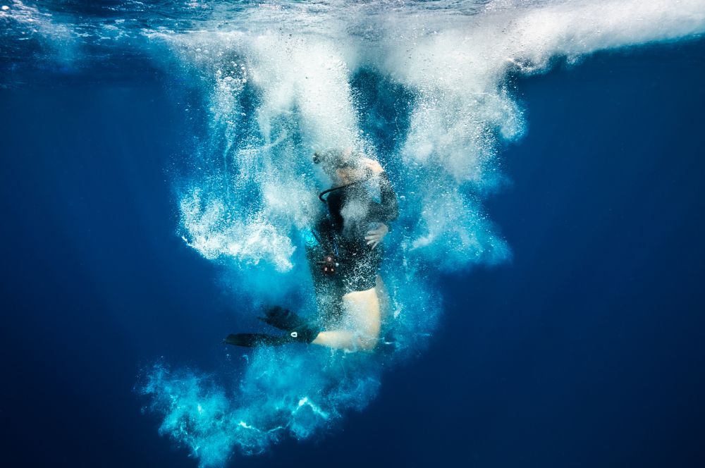 Divers entering the water negatively weighted due to surf