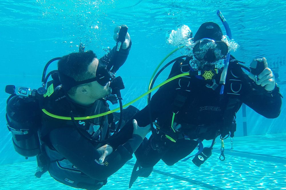 A scuba diver and a dive master in a pool, demonstrating scuba diving skills