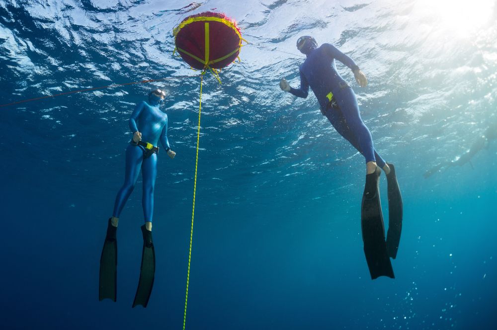 Two freedivers diving together and practicing teamwork in deep freediving