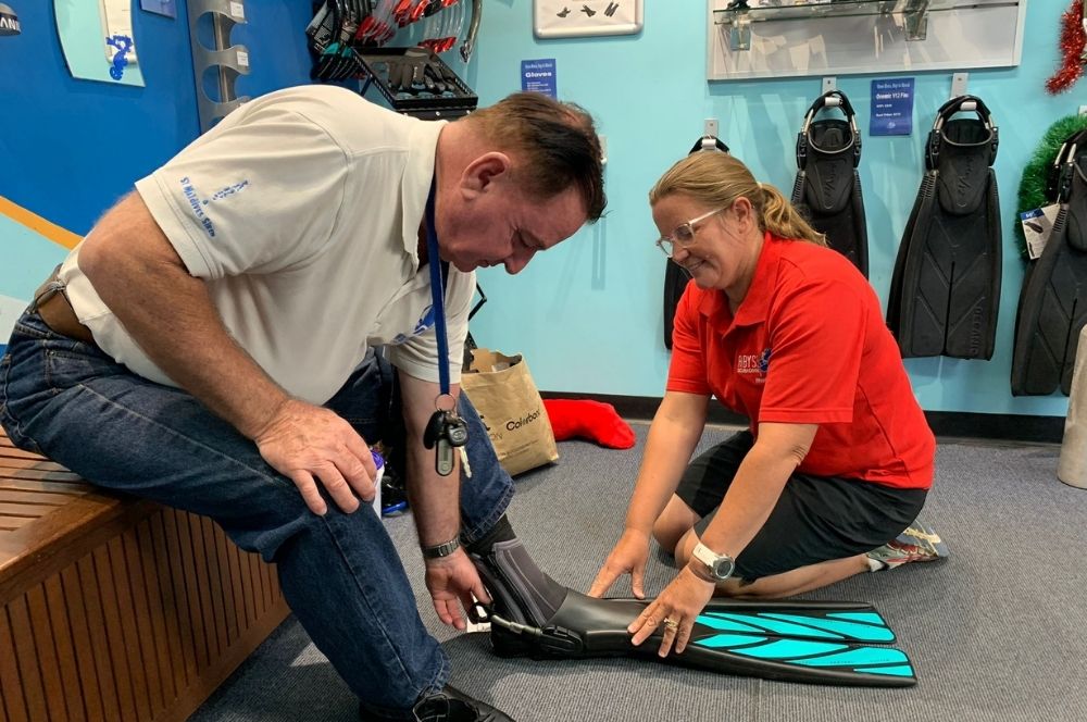 A diver in a dive shop talking to a dive instructor