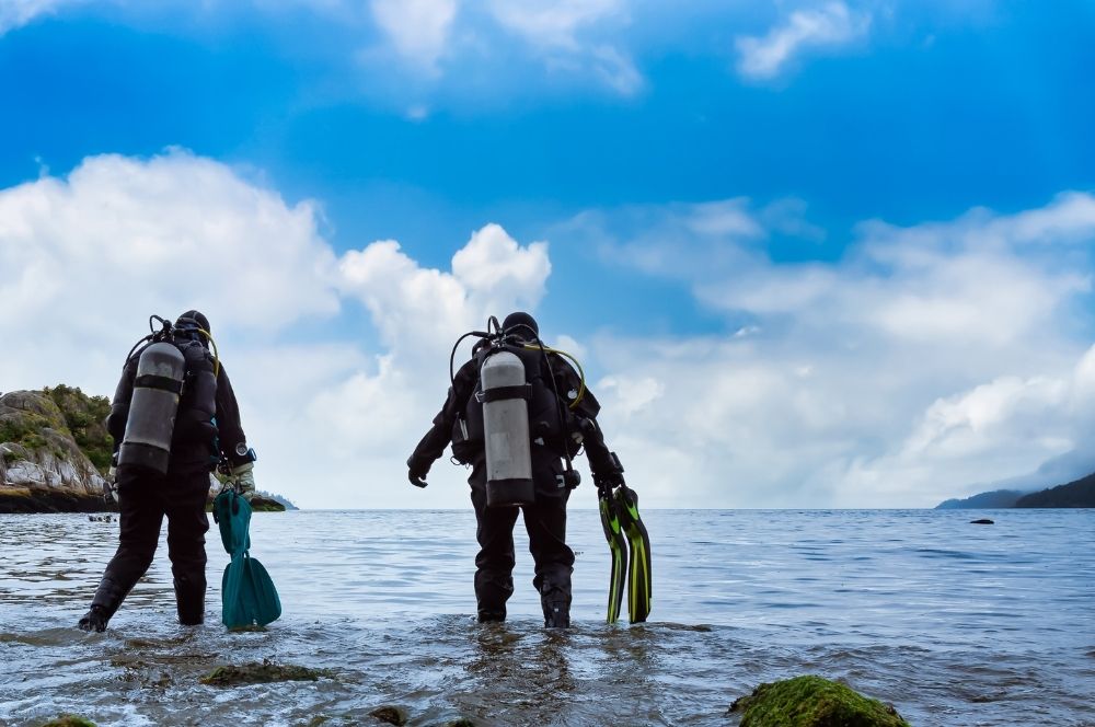 Scuba diver in the ocean with another diver about to start a dive