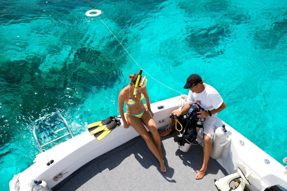 A scuba diver with a dive master on a dive boat