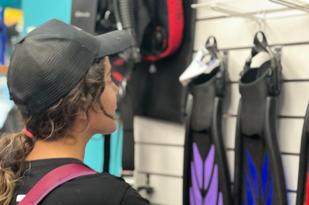 A diver inspecting the range of fins in thier local dive shop