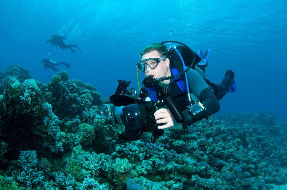 Dive guide with a camera during a dive trip, to capture memories for his divers