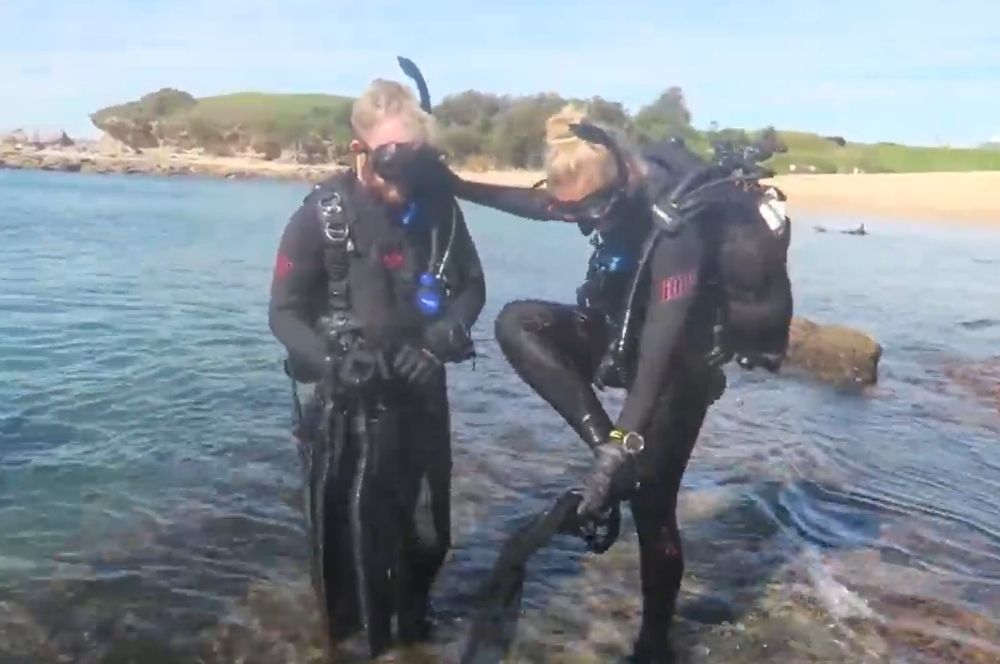Donning fins on a shore dive