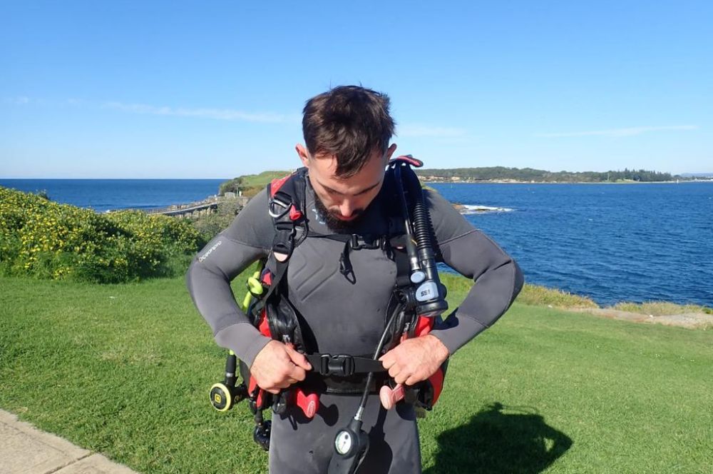 A scuba diver in the ocean, checking and maintaining scuba equipment