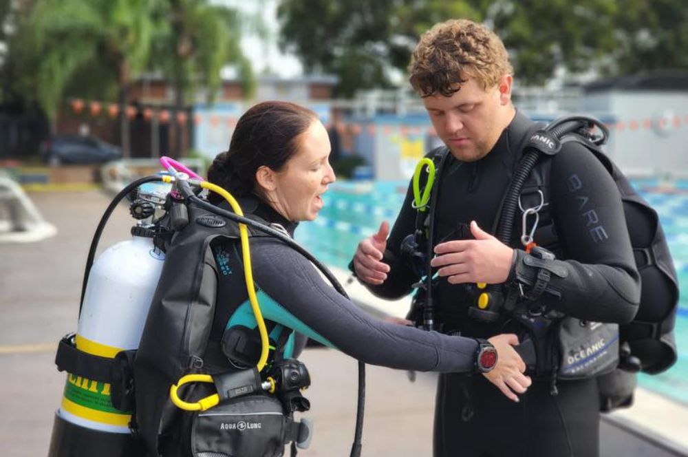 A scuba diver in the swimming pool with a instructor, buddy check