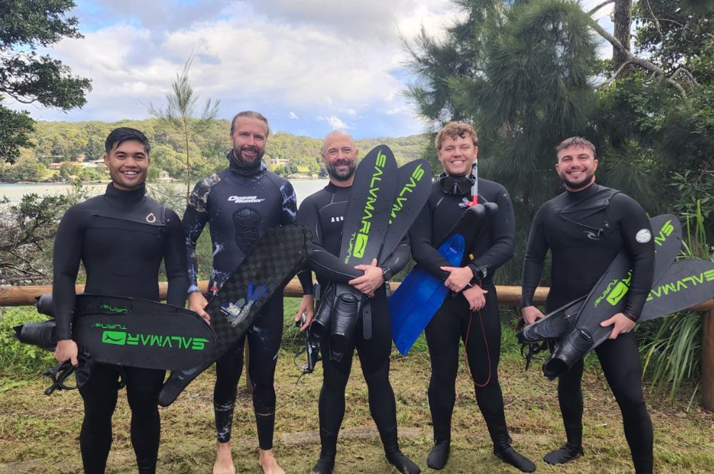 A group of students taking a freediver course in crystal clear waters, surrounded by colorful marine life.