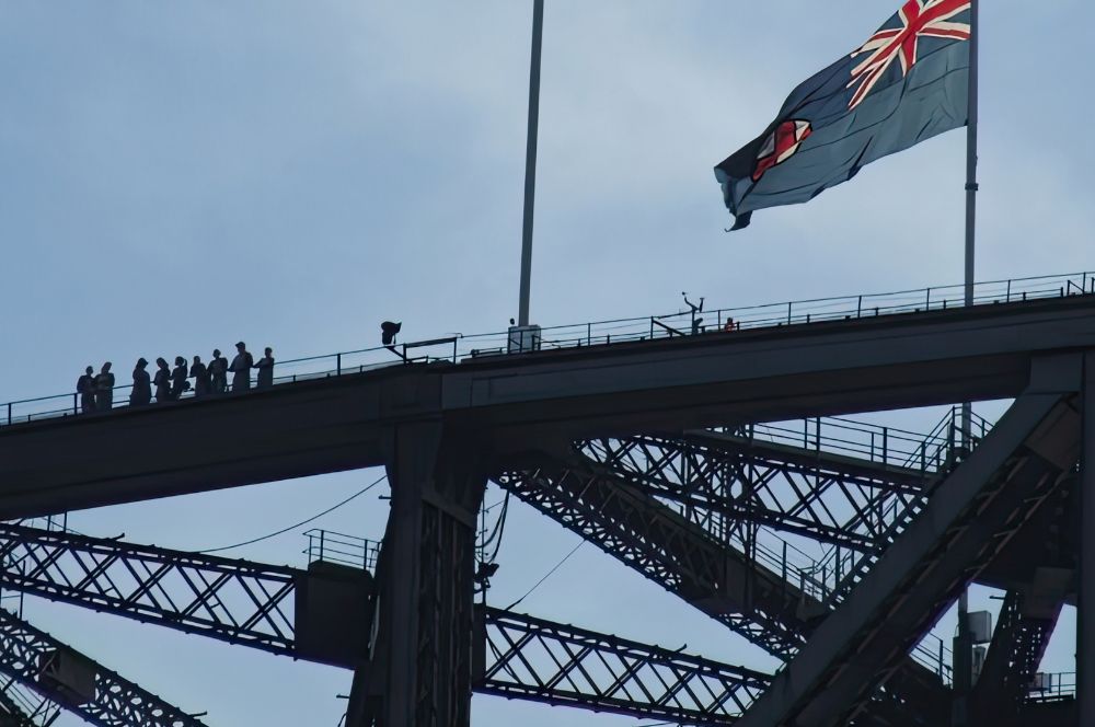 International students climbing Sydney Harbour Bridge with a perfect view of Sydney Opera House