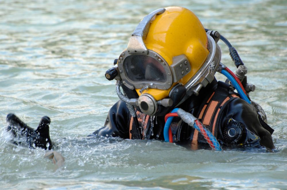 A comercial diver performing their job duties in a challenging work environment with physical demands, typical of diver jobs.