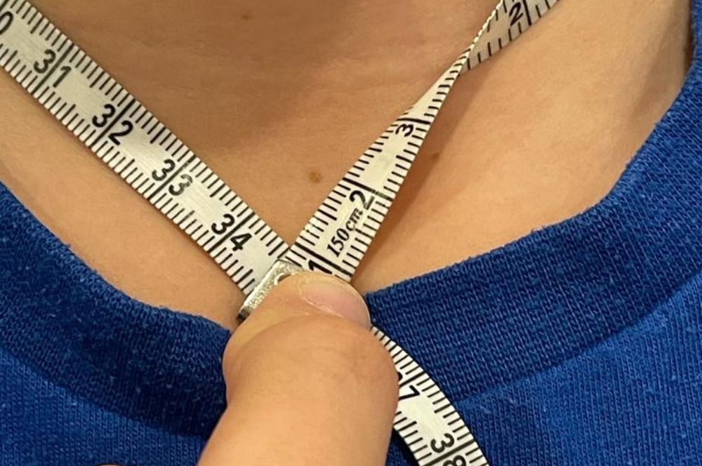 A person measuring their neck size for a neck weight