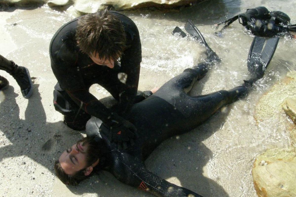 A scuba diver performing first aid on another diver