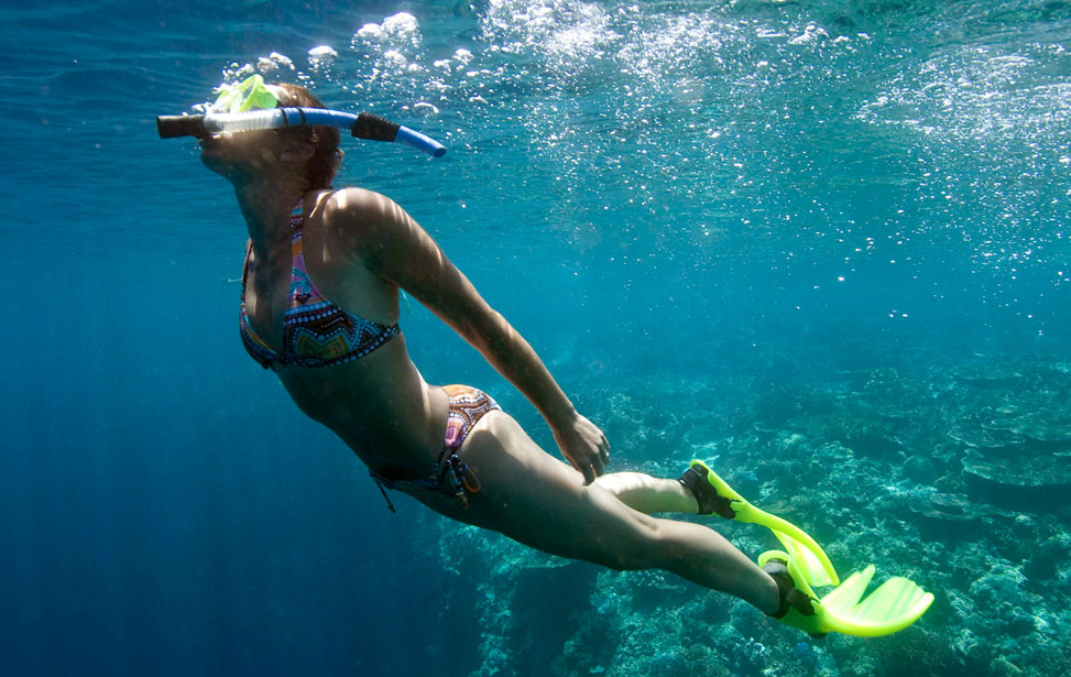 A person snorkeling and taking deep breaths underwater